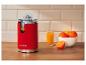 Presse-agrumes rouge avec jus d'orange et oranges sur un comptoir en bois.