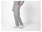 Un homme porte un pantalon de survêtement gris avec le logo LV et des baskets blanches.