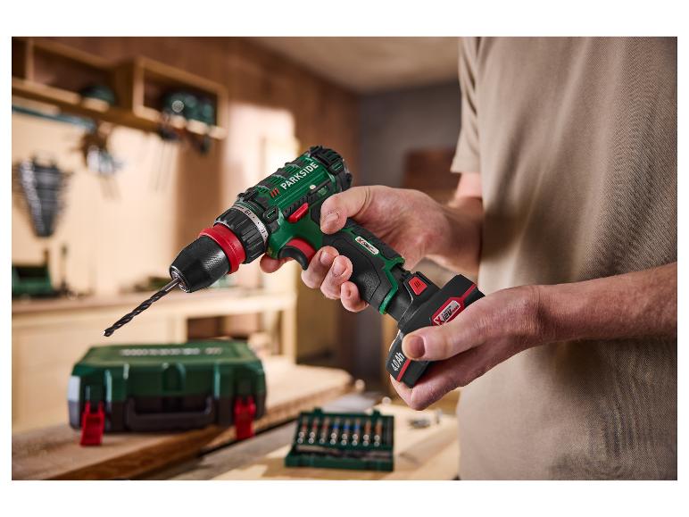 Homme tient une perceuse sans fil PARKSIDE® 12 V avec batterie 4 Ah dans un atelier.