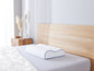 Un oreiller blanc avec une bordure bleue sur un lit avec une couette blanche.