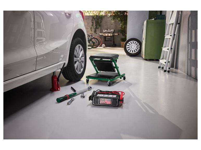 Cric de voiture, clé dynamométrique et chargeur de batterie dans un garage pour changer un pneu.