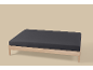 Un cadre de lit en bois avec un drap-housse gris foncé sur fond clair.