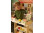 Enfant jouant avec une caisse enregistreuse jouet et de la nourriture factice, dont de la viande, du fromage et du poisson.