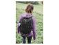 Une femme avec un sac à dos noir Crivit marche dans l'herbe.