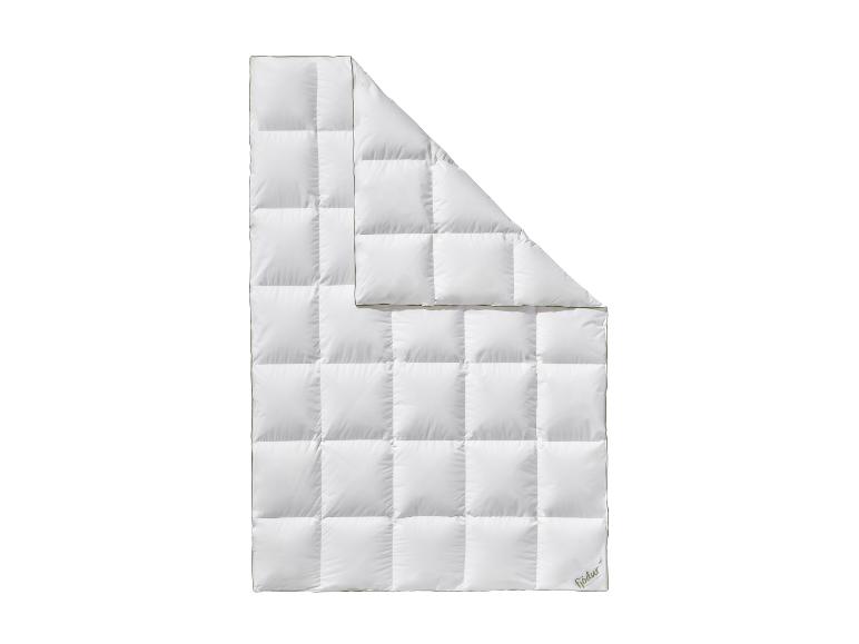 Couette blanche matelassée avec un coin plié, affichant un logo vert dans le coin inférieur droit.