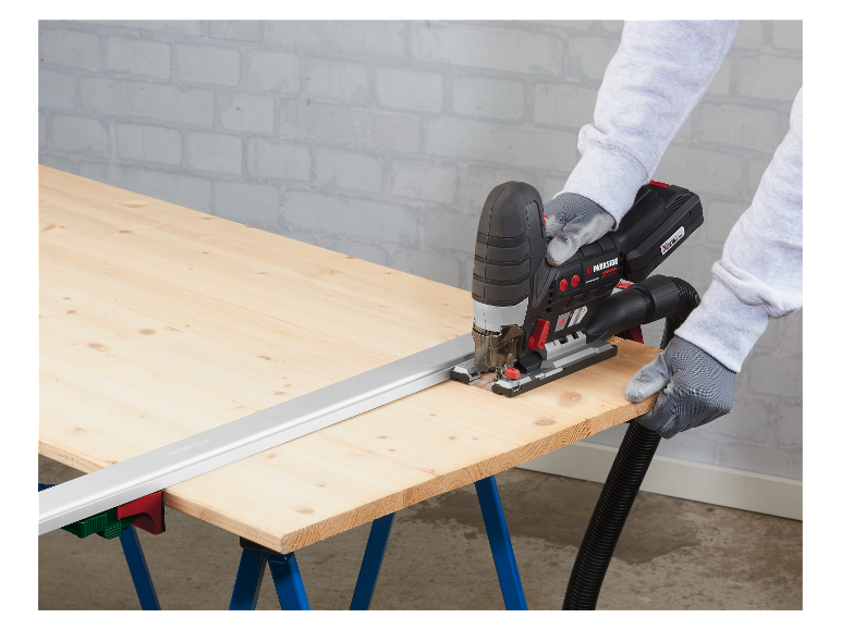 Une personne utilise une scie sauteuse Parkside pour couper du bois sur une table de travail.