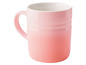 Une tasse Le Creuset rose avec un effet ombré.