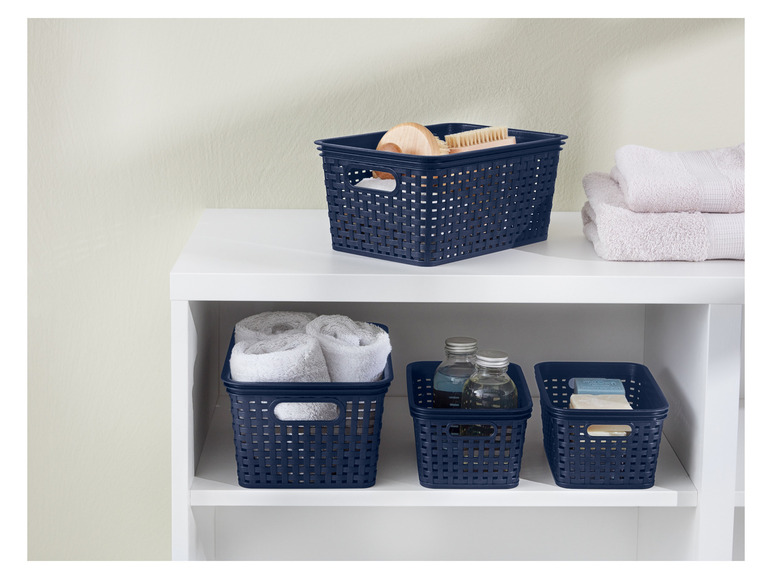 Panier de rangement bleus avec poignées, remplis de serviettes et d'articles de toilette