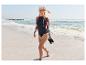 Femme en ensemble de snorkeling CRIVIT et lycra marchant sur une plage de sable.