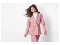 Femme en tailleur rose avec blazer et pantalon, les cheveux au vent