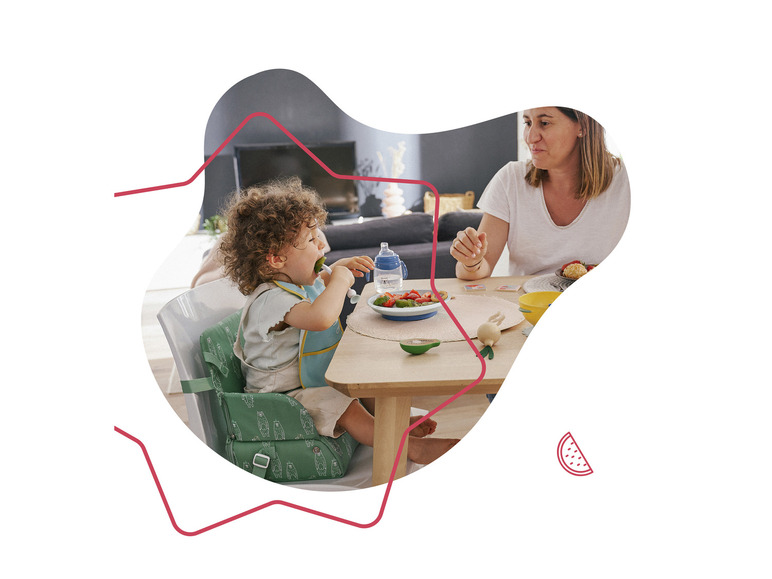 Un enfant mange sur une chaise haute Stokke Tripp Trapp avec un adulte.