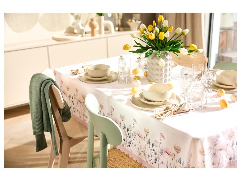 Table de Pâques dressée avec nappe à fleurs, vaisselle beige et vase de tulipes jaunes et blanches.