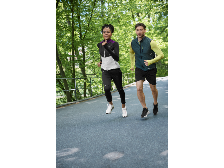 Deux coureurs en tenue de sport faisant du jogging en extérieur, femme en veste et homme en gilet.