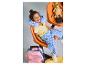 Une fille souriante portant un coussin de cou bleu Hello Kitty, assise sur une chaise orange.