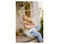 Femme enceinte dans un fauteuil suspendu sur un balcon avec plantes et sol carrelé.