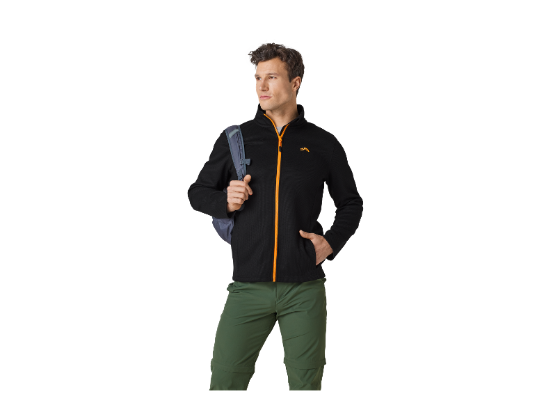 Homme portant une veste noire et un pantalon vert de randonnée.
