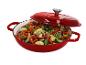 Cocotte en fonte rouge avec couvercle, remplie de légumes sautés.