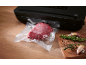 Viande sous vide avec une machine sous vide et des épices sur une planche en bois.