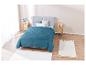 Couverture matelassée turquoise sur un lit, tapis moelleux.