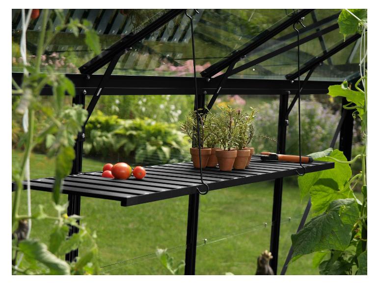Une serre en métal noir avec une étagère en bois et des plantes en pot