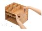 Personne assemblant un organisateur de bureau en bois clair à plusieurs compartiments.