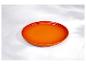 Assiette ronde orange sur une surface en marbre blanc avec des ombres.