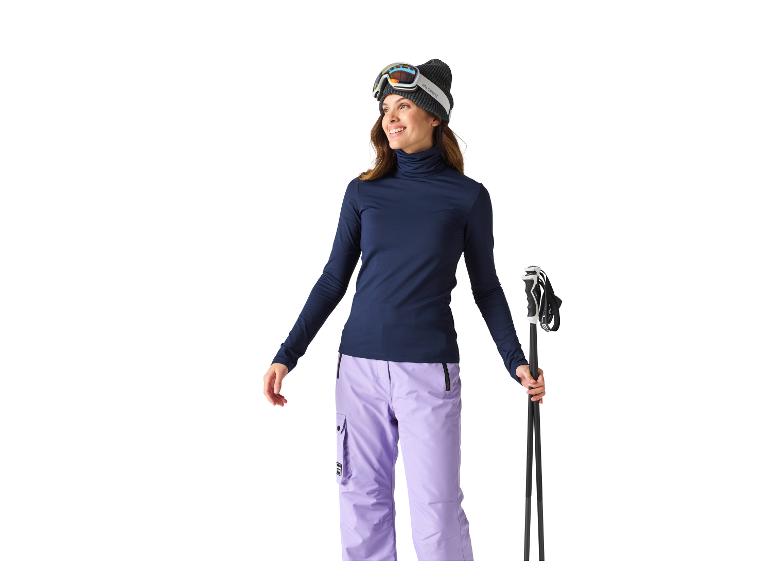 Skieuse portant un bonnet, des lunettes de ski, un col roulé et un pantalon de ski.