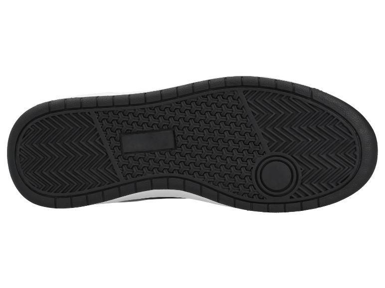 Semelle noire d'une chaussure de sport avec motif d'adhérence et logo rectangulaire.