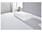 Un oreiller blanc avec une housse matelassée sur un lit blanc.