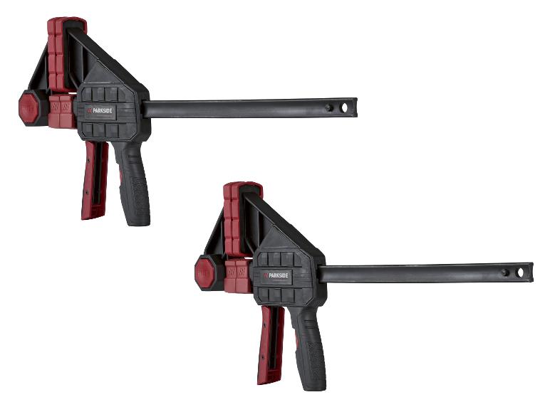 Deux serre-joints à barre rouges et noirs avec mécanisme de libération rapide.