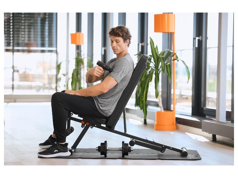 Homme assis sur un banc de musculation utilisant un masseur CRIVIT sur un Bodenschutzmatte.