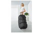 Une femme tirant une valise noire à roulettes.