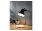 Une lampe de bureau noire avec un clip, un perforateur et un carnet sur un bureau en bois.