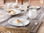 Table dressée avec assiettes, tasses, verres en porcelaine blanche et petites pâtisseries.
