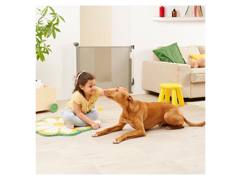 Une fillette caresse son chien près d'une barrière de sécurité.