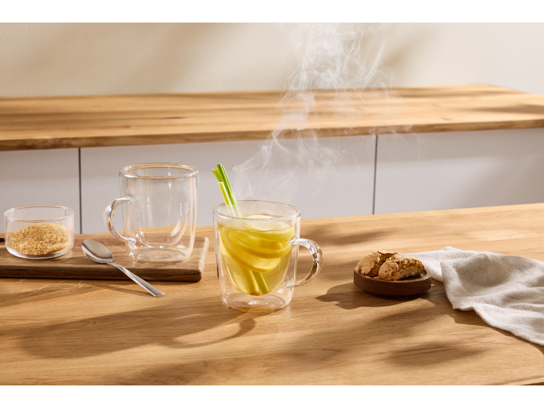 Thé au citron chaud fumant, sucre roux et biscuits sur une table en bois.