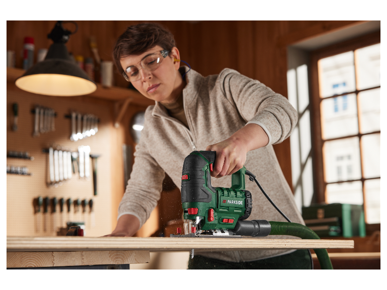 Une femme utilise une scie sauteuse Parkside dans son atelier.