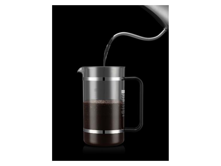 De l'eau est versée d'une bouilloire dans une cafetière à piston avec du café moulu.