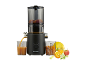 Extracteur de jus noir avec fruits et jus dans un verre.