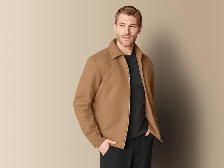 Un homme portant une veste marron et un pull noir.