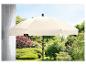 Un parasol beige dans un jardin avec des arbres verts.
