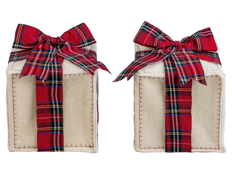 Deux boîtes cadeaux crème avec des rubans écossais rouges sur fond noir.