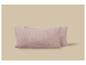 Deux oreillers rectangulaires rose pâle en tissu gaufré sur fond beige.