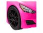 Gros plan d'une voiture jouet rose avec des jantes noires et un phare.