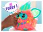 Furby coloré avec une fourrure rose et des oreilles bleues, une main touchant sa tête.