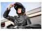 Une femme portant un casque de moto et une veste en cuir sur une moto.