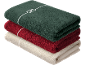 Pile de serviettes pliées vert foncé, rouge et beige, la supérieure avec un nœud blanc.