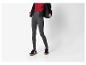 Femme en legging gris, haut rouge et veste noire.