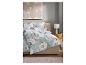 Chambre à coucher avec lit aux draps fleuris, lampe de chevet et tableau abstrait.