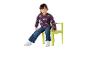 Enfant souriant en pull arc-en-ciel violet et jean assis sur une chaise verte.